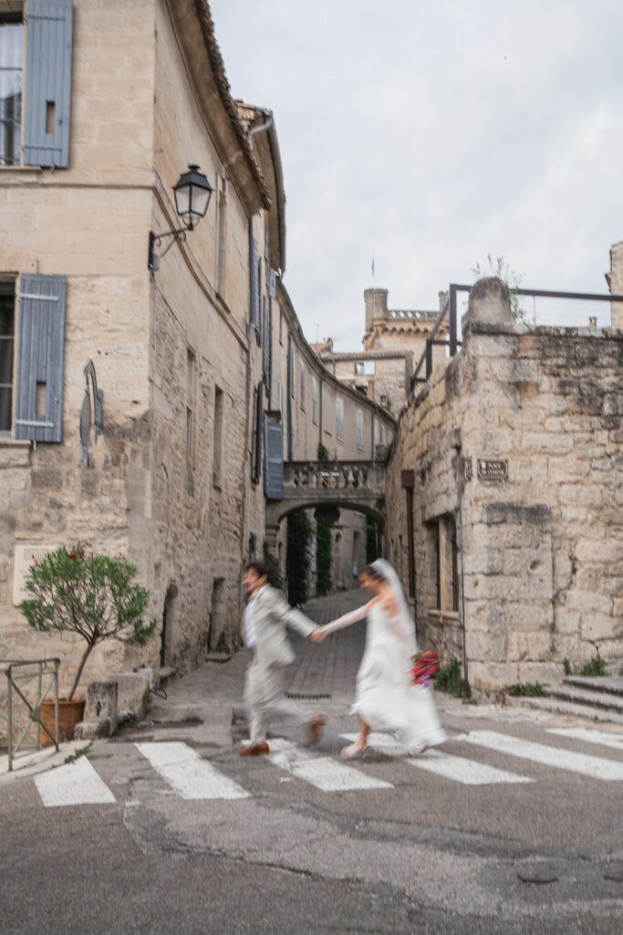 Joséphine et Baptiste traversent une ruelle d'Uzès en direction de la Tour Fenestrelle le jour de leur mariage